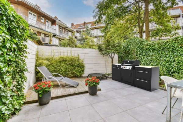 Bucatarie exterior BBQ KItchen in gradina, cu cladiri pe fundal.